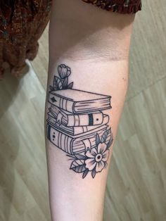 a person with a tattoo on their arm holding a stack of books in her hand