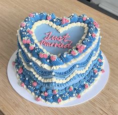 a blue heart shaped cake on top of a wooden table with the words just married written on it