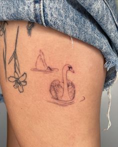 a close up of a person's stomach with a tattoo on her leg and a swan in the water