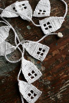 white crocheted ornaments are hanging on a wooden surface, with string attached to them