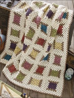 a white crocheted blanket sitting on top of a wooden floor