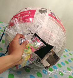 someone is wrapping up a paper mache ball with plastic wrap and some other items