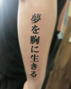 a person with a tattoo on their arm that has chinese characters written in black ink