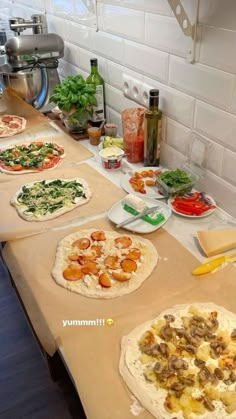 several different types of pizzas are on the counter in this kitchen, including one with mushrooms and spinach