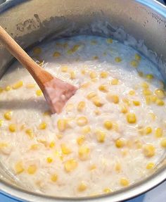 a wooden spoon stirring corn in a pot