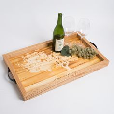 a bottle of wine and some grapes on a wooden tray