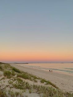 two people are riding horses on the beach at sunset or dawn with one person in the distance