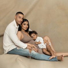 a man, woman and child are sitting on a couch with their arms around each other