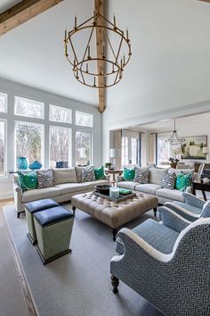 a living room filled with furniture and a chandelier hanging over the top of it