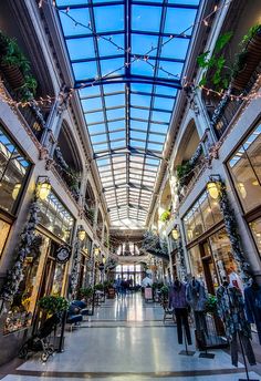 the inside of a shopping mall filled with lots of windows and plants hanging from the ceiling