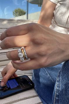 a woman's hand with a ring on her finger next to a cell phone