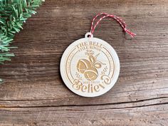 a wooden ornament hanging from a christmas tree on a table with pine branches