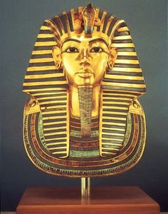 an egyptian mask is displayed on a wooden stand