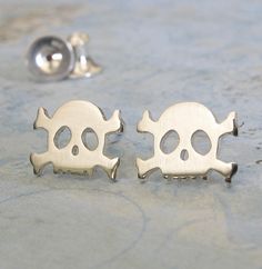 Simple artisan dainty handmade skull and crossbones earrings. The Details ∞ Artisan handmade jewelry ∞ Small Skull and crossbones studs (approx 6.5mm x 8.7mm) ∞ Choose from sterling silver, 14k gold-filled or solid 14k yellow gold ∞ Earring backs included in the metal of your choice ∞ Made to order ∞ Gift box included ∞ Made in the USA IMPORTANT NOTE FOR 14K GOLD FILLED EARRINGS If you are purchasing our gold filled stud earrings please keep in mind they are cut from a sheet of 14k gold filled m Gold Skull Earrings Nickel Free, Sterling Silver Skull Earrings For Gift, Handmade Metal Skull Earrings, Nickel-free Skull Earrings In Punk Style, Metal Skull Single Earring, Handmade Sterling Silver Skull Earrings, Nickel-free Sterling Silver Skull Jewelry, Gold Skull-shaped Earrings, Handmade Skulls