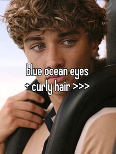 a young man with curly hair is looking at the camera