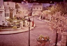 a street scene with an old fashioned bicycle parked on the side of the road and trees in bloom