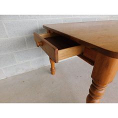 a wooden table with drawers on it in front of a brick wall and cement floor