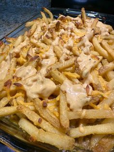 french fries covered with cheese and sauce in a glass casserole dish on a counter