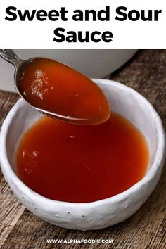 a spoon full of sweet and sour sauce in a white bowl on a wooden table