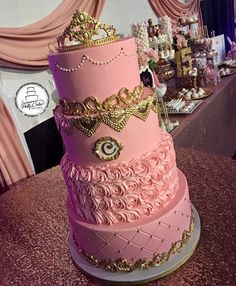 a three tiered pink cake with gold trimmings on it's sides