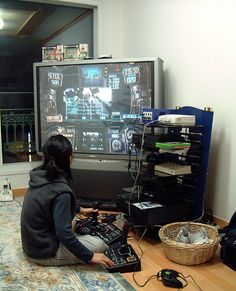 a person sitting on the floor in front of a flat screen tv playing video games