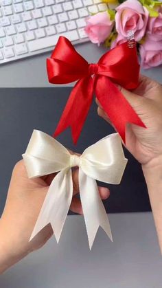 a person holding a red and white bow in their hand next to a computer keyboard