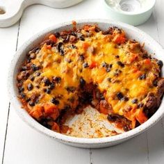 a casserole dish with cheese and black beans in it on a white table