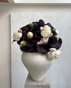 a white vase with black and white flowers in it