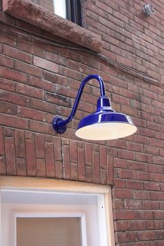 a blue light on the side of a brick building next to a white door and window