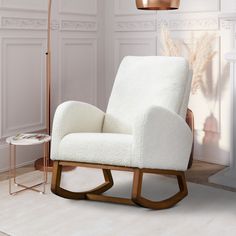 a white rocking chair sitting in a living room next to a lamp