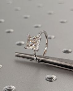 a diamond ring sitting on top of a piece of metal