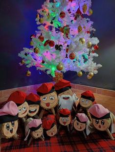 a group of stuffed toys sitting next to a christmas tree