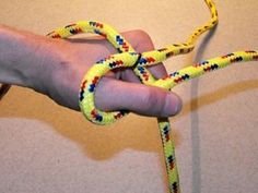 a hand holding a yellow rope with multicolored ropes on it's end