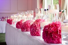 the table is set up with candles and pink flowers on it for a wedding reception