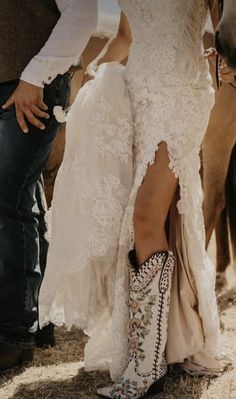 a man and woman standing next to each other with cowboy boots on their feet in front of horses