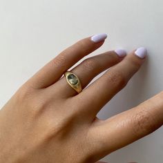 a woman's hand wearing a gold ring with an oval shaped diamond on it