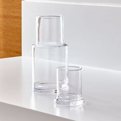 two clear glass vases sitting on top of a white counter next to each other