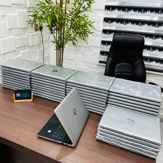 a stack of laptops sitting on top of a wooden desk next to a chair