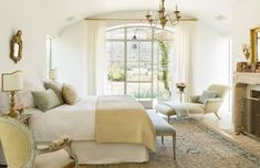 a bedroom with a large bed, fireplace and chandelier in the middle of it