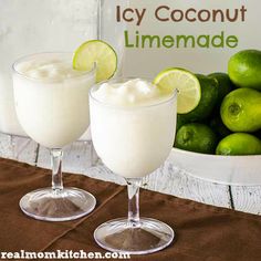 two glasses filled with ice cream and limes next to a sign that says icy coconut limeade