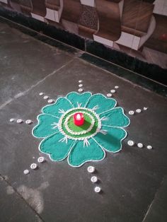 a green and white flower on the ground next to a red ball in it's center