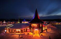 a lit up building in the middle of a snow covered field with people walking around it