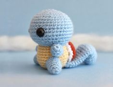 a small crocheted turtle sitting on top of a blue surface with a black eye