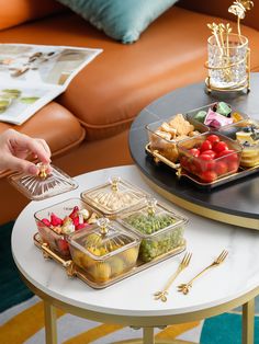 a table topped with trays of food next to a couch