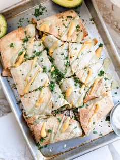 a tray filled with flatbreads covered in cheese and sauce next to an avocado