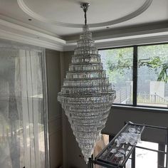 a large crystal chandelier hanging from the ceiling in a living room next to a window