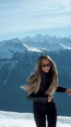 a woman standing on top of a snow covered slope