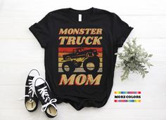 a monster truck mom shirt on top of a white table next to a pair of sneakers