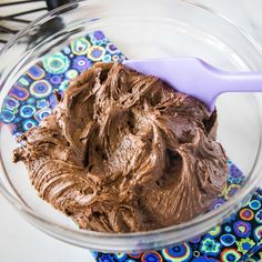 a glass bowl filled with chocolate frosting on top of a blue and white napkin