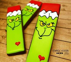 two green and red candy sticks with faces painted on them, sitting on a wooden table